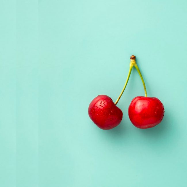 Couple of Red Cherries on the Green Stem with Blue Background — Wholesale Food in Coffs Harbour, NSW